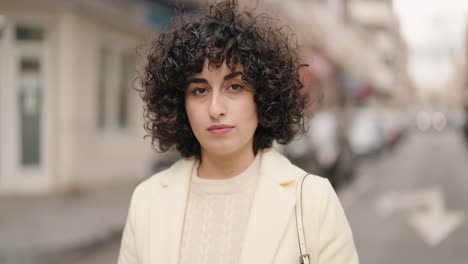 young woman standing with serious expression at street