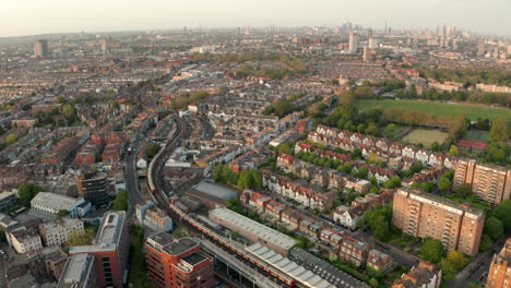 Aerial-shot-over-District-line-underground-train-in-west-london-neighbourhood-Fulham-looking-towards-the-city-skyline