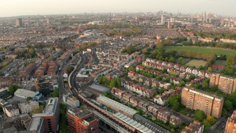 aerial shot over district line underground train in west london neighbourhood fulham looking towards the city skyline