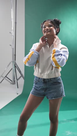 vertical video: confident young woman posing in denim shorts in photography studio