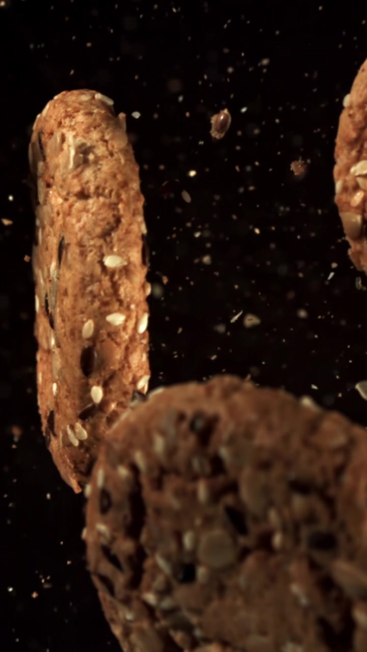 Seeded Oatmeal Cookies Falling in Slow Motion on Black Background
