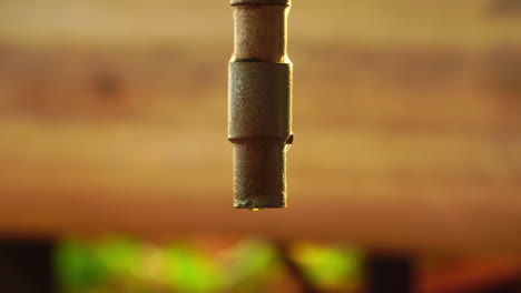 Antiguo-Grifo-De-Aspecto-Vintage-Goteando-Gotas-De-Agua-Con-Reflejo-De-Luz-Sobre-Fondo-De-Madera,-Vista-De-Cerca