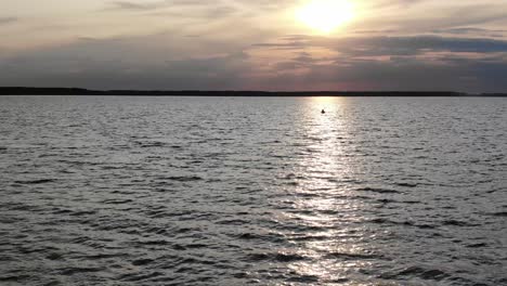 Niedrige-Luftaufnahme,-Die-Bei-Sonnenuntergang-Auf-Ein-Silhouettiertes-Kanu-Auf-Dem-Fluss-Zufliegt