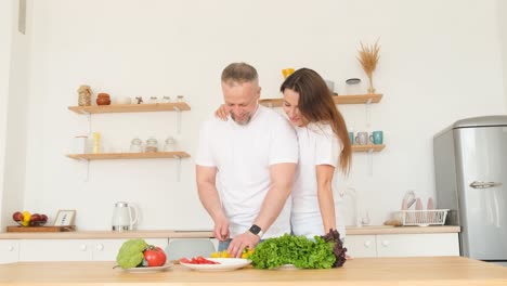 an attractive middleaged man is preparing food for his wife in a modern kitchen an attractive middleaged man is preparing food for his wife in a modern kitchen couple in love at home healthy family dinner