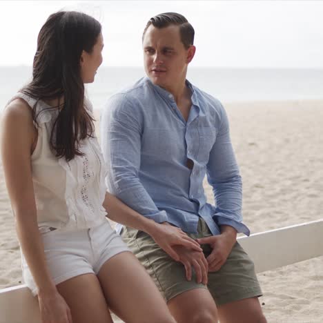 Man-and-woman-vacationers-relaxing-together-at-coastline