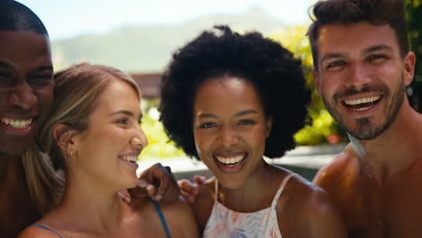 portrait of group of smiling multi-cultural friends on holiday in swimming pool