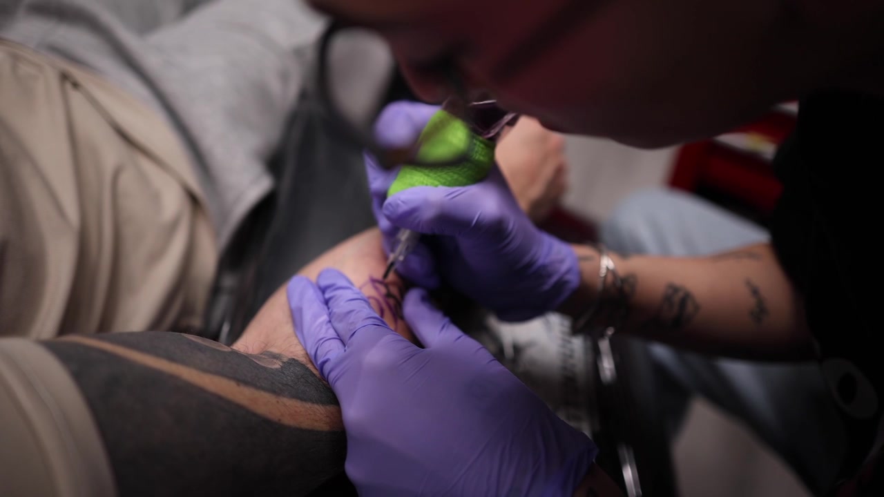 Tatuatore che lavora sul braccio di un cliente in uno studio