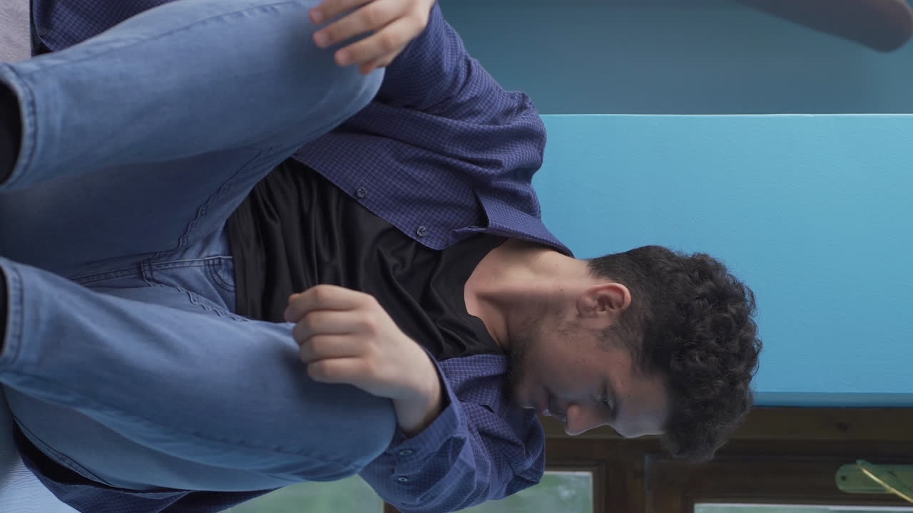 분노로 벽을 때리는 남자의 수직 비디오입니다.