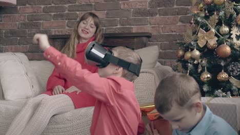 kid plays with vr headset near mother and little brother