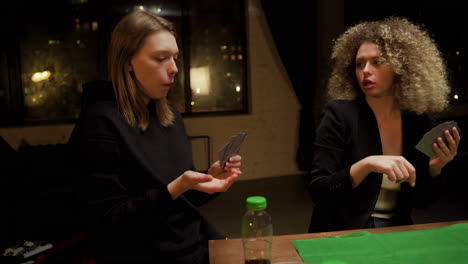 Group-Of-Friends-Playing-Poker-Sitting-On-Chairs-At-A-Table-At-Home-4