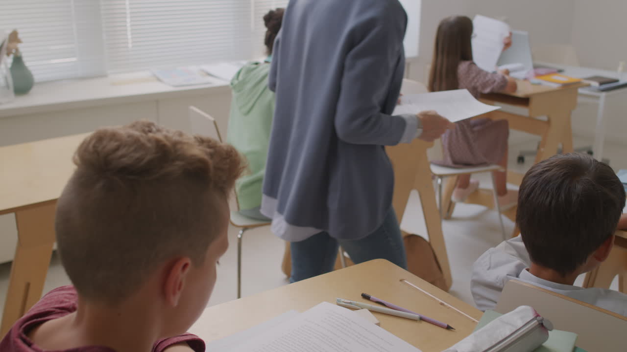 Teacher Giving Test Sheets to Children in Class