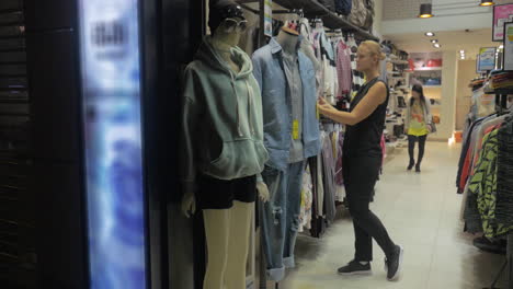 Mujer-Rubia-Sonriendo-Mientras-Elige-Blusas-En-La-Tienda-De-Hong-Kong,-China