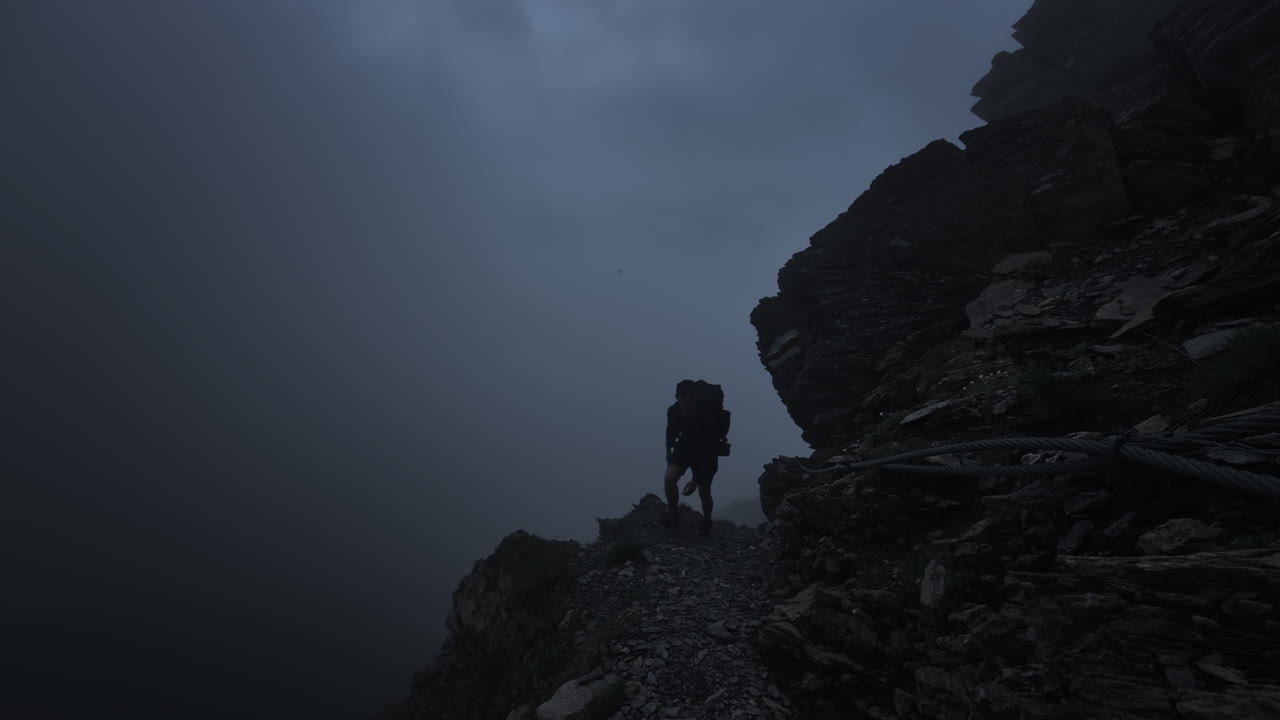 Silhouette di un escursionista su un sentiero di montagna nebbioso