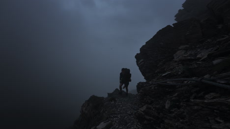 silhouette of a hiker on a foggy mountain path