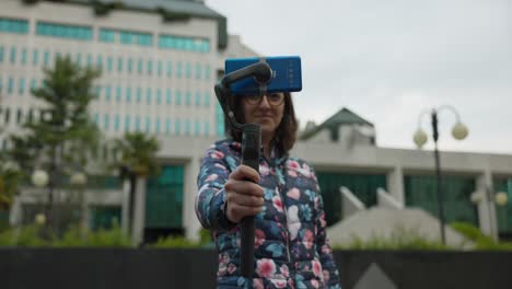 youtuber femenina e influyente social sosteniendo un estabilizador gimbal y un teléfono inteligente giratorio