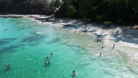 Aerial-landscape-view-of-a-people-bathing-on-a-tropical-beach-in-Playa-Blanca,-Costa-Rica