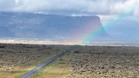 Cars-Driving-Through-Ring-Road-With-Lomagnupur-Mountain-And-Rainbow-In-South-Iceland