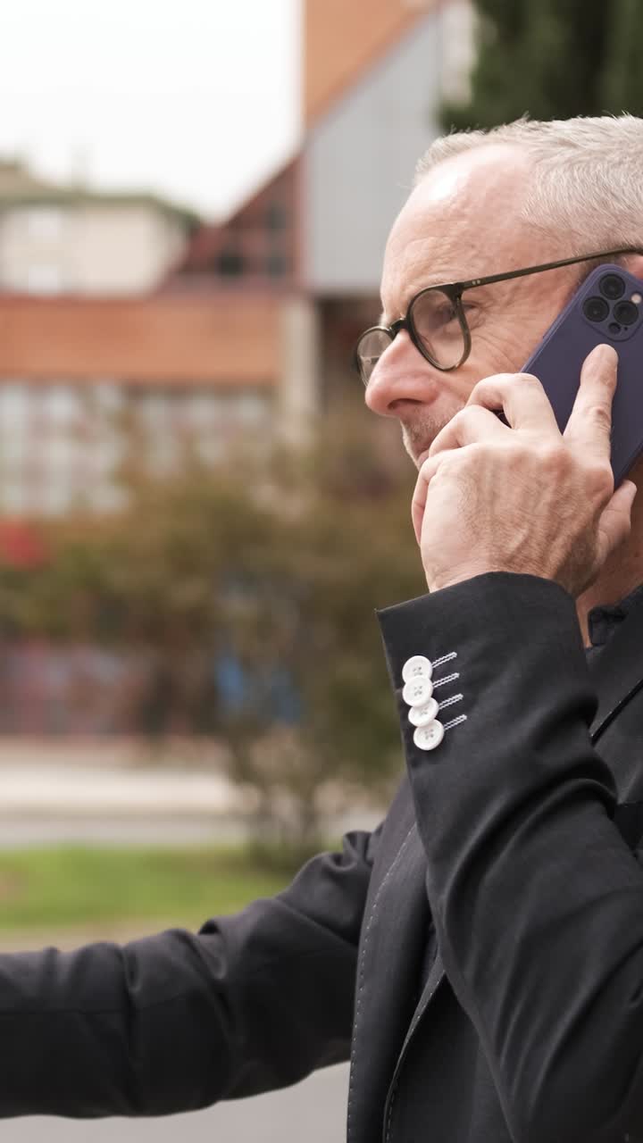 Uomo d'affari impegnato in una seria conversazione telefonica con gesti espressivi. Verticale