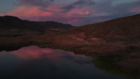 aerial sideways movement of the sunsets pink reflection off clouds, with pond reflections