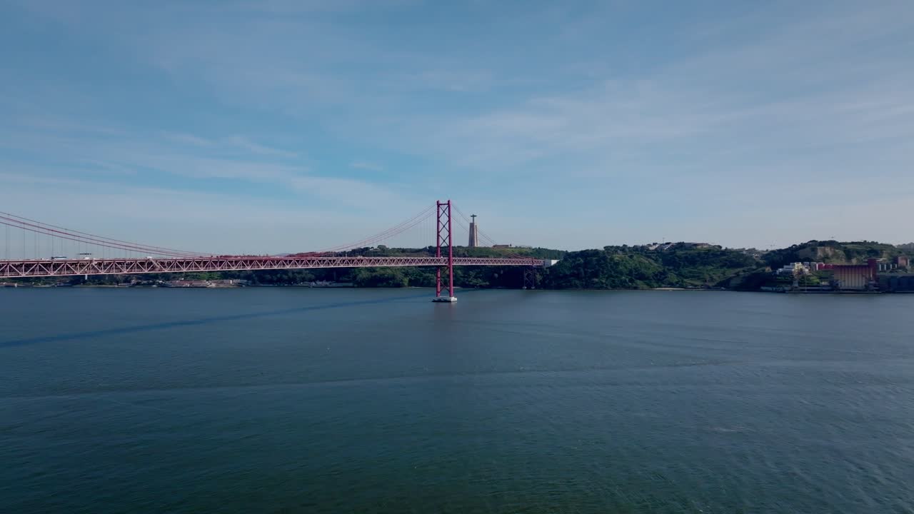 Panning drone shot of bridge and river in Lisbon.