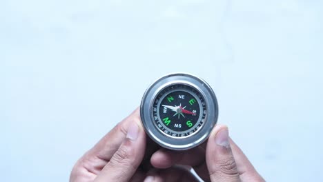 mano sosteniendo una brújula sobre un fondo blanco