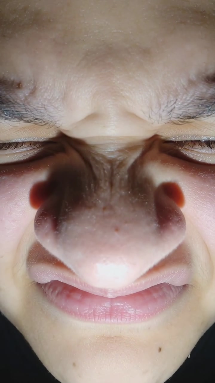 Vertical video: Front LED flashing, teen leaning to phone for selfie, turning and squinting in room