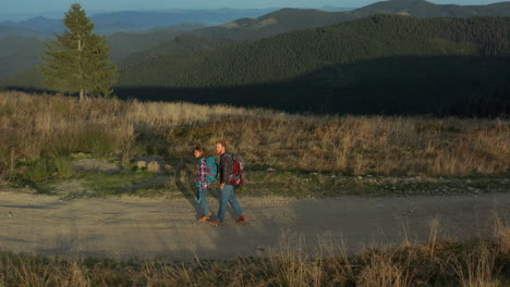 drone tourists backpacks walking mountains path talking against green hills