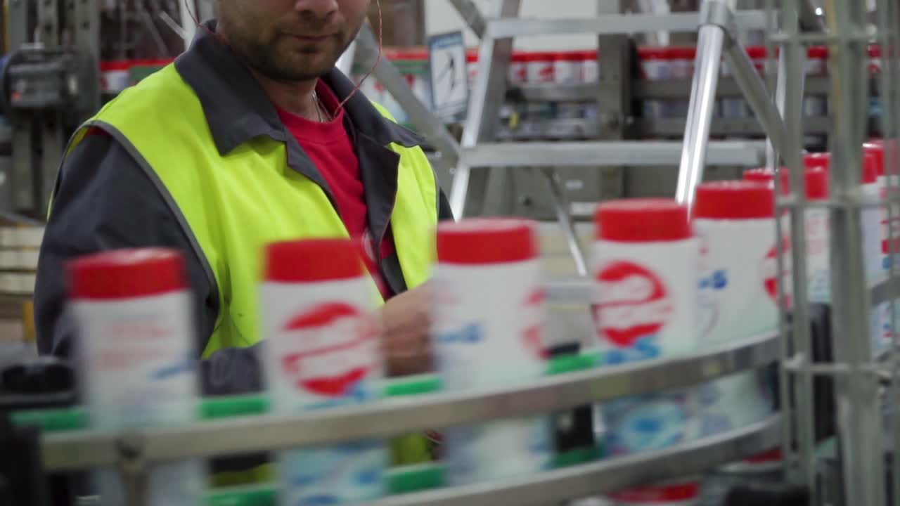 Factory worker checking spray bottles on a conveyor belt