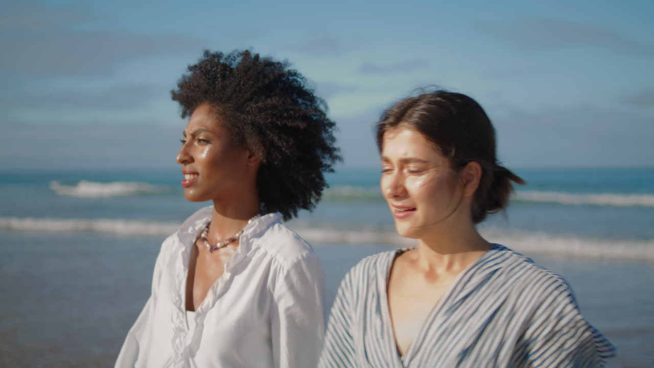 Two girls talking sea shore closeup. Carefree lesbian couple walking ocean coast