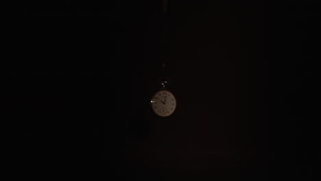 pocket watch swings and stop on a dark background