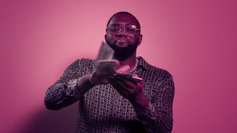 happy man holding stack of money indoors. afro guy throwing dollars in studio