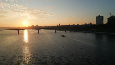 sunset over a river with a bridge and city skyline
