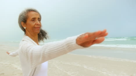 side view of active senior african american woman exercising on exercise mat at the beach 4k