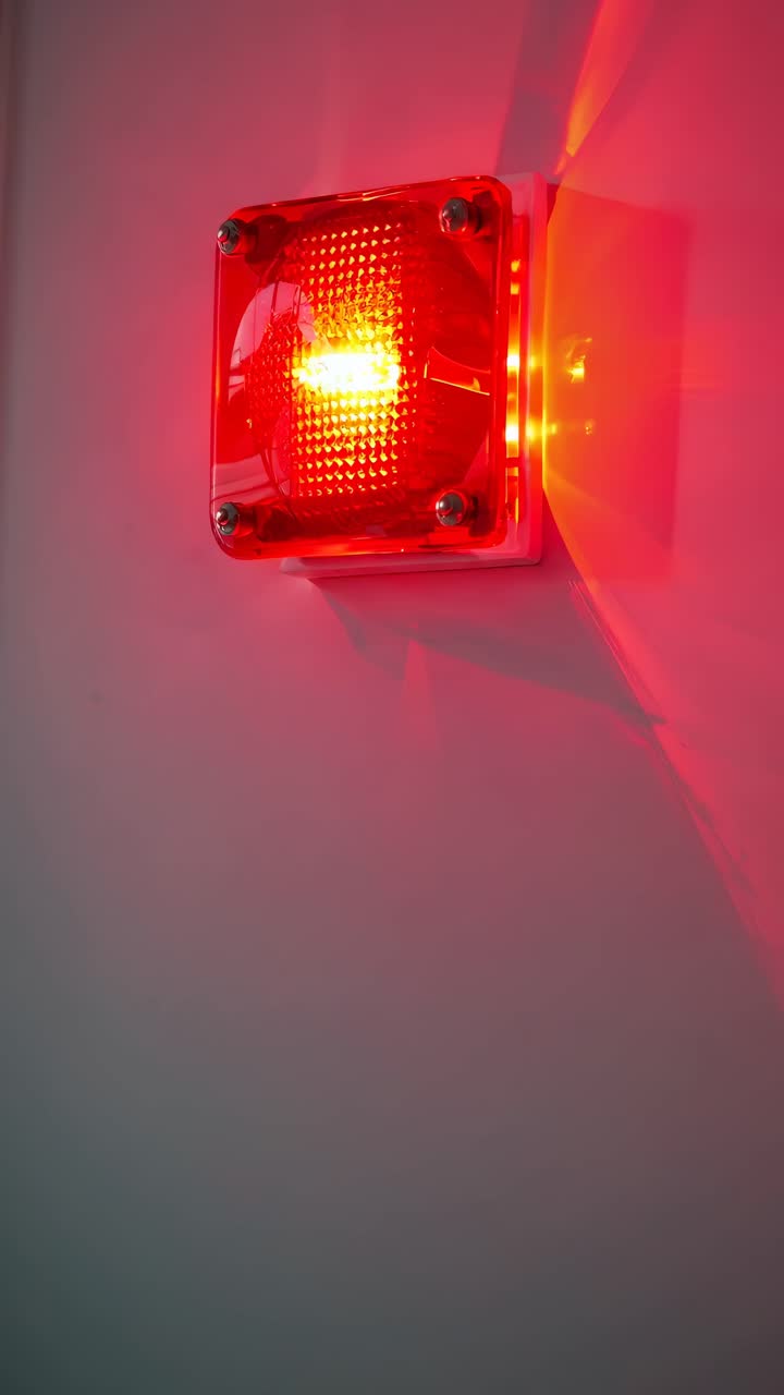 A dimly lit hallway with a red alarm light on the wall, captured from a low angle