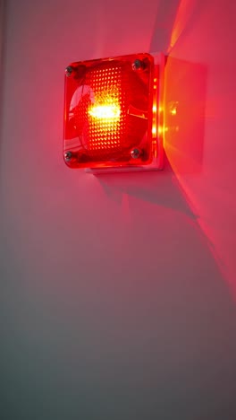 a dimly lit hallway with a red alarm light on the wall, captured from a low angle