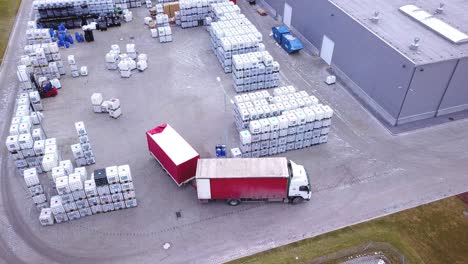 forklift trucks move between large shelves at outside warehouse and load pallets