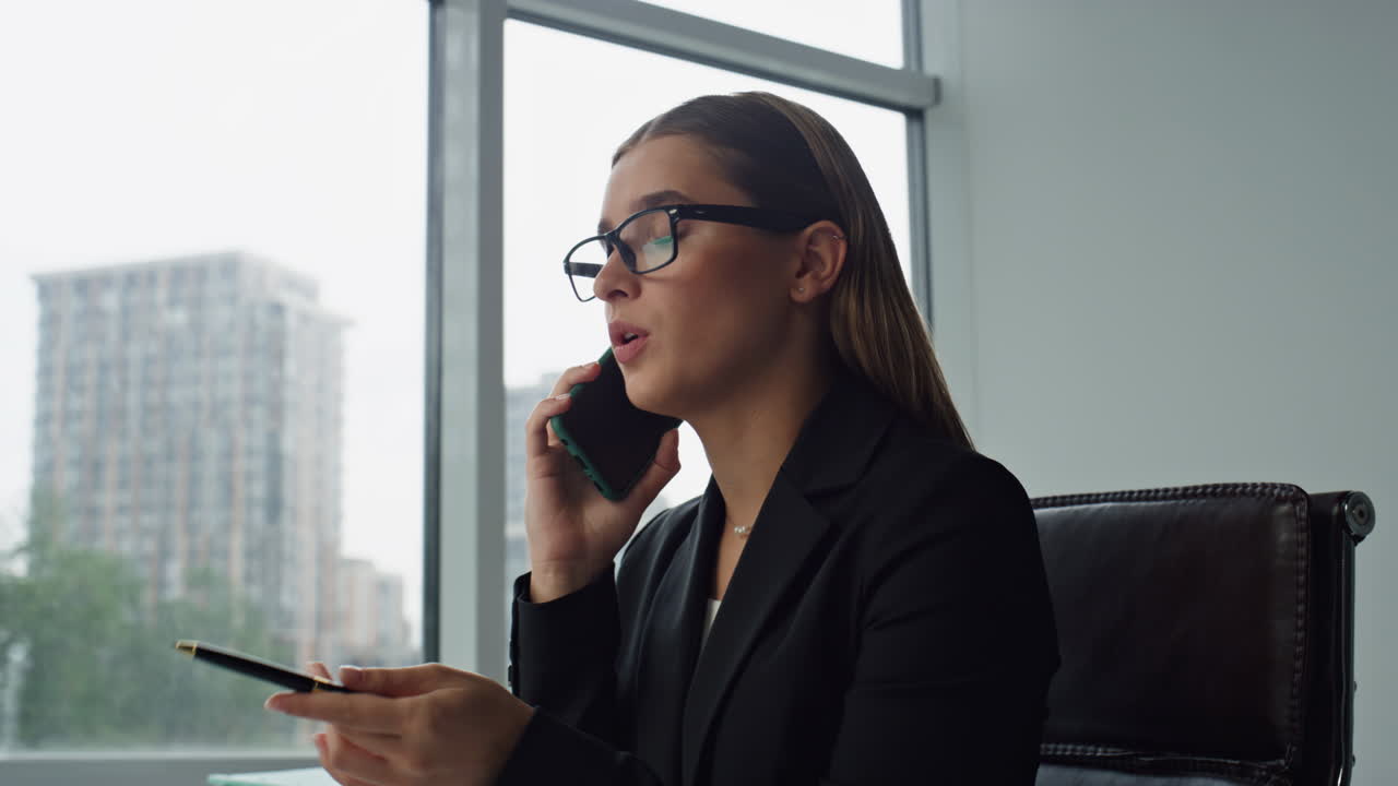 Donna dirigente parla allo smartphone in ufficio, primo piano. Manager concentrata in consulenza.
