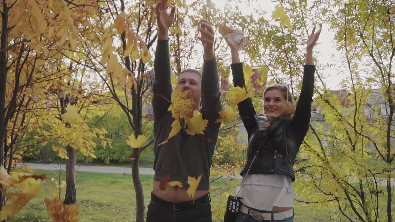 пара играет с осенними листьями в парке