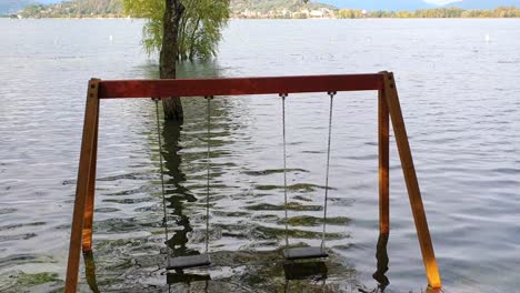 swing for children of playground flooded by flood of lake after long rains