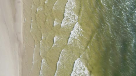 tropical beach aerial view, top view of waves break on tropical white sand beach. sea waves seamless loop on the beautiful sand beach.