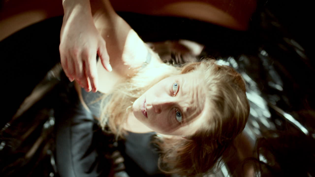 Female Dancer Sitting among Distorted Reflections, Looking Up Expressively