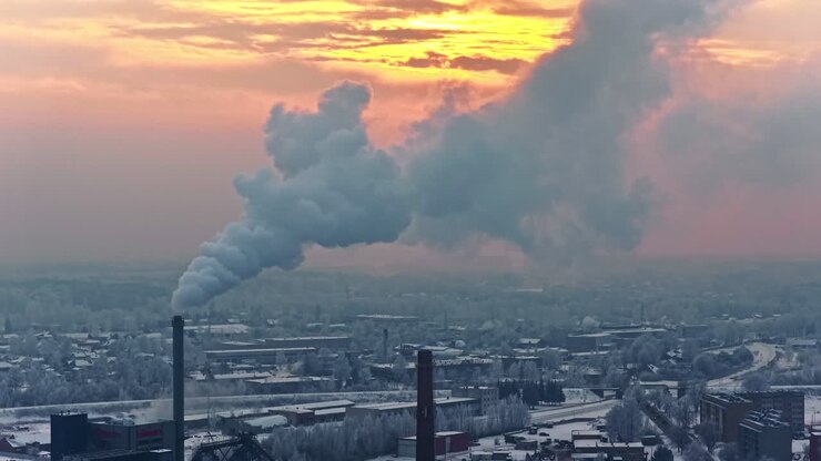 Inquinamento atmosferico industriale. Pennacchio di fumo che si alza da una ciminiera in una fabbrica chimica durante il tramonto. Ripresa aerea.