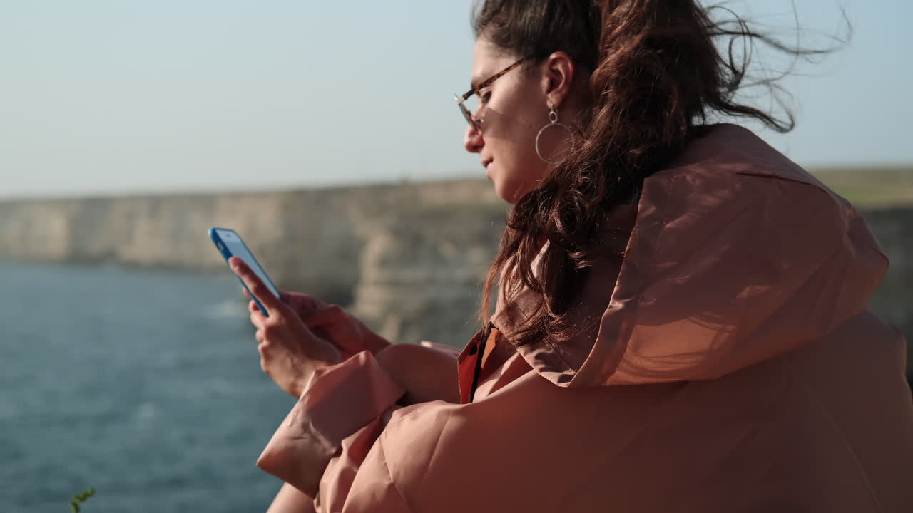 Woman using phone by the seaside