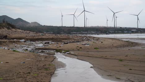 playa contaminada con parque eólico visto en el fondo en son hai, vietnam