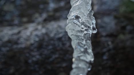 ice icicle over a blurry background and rocky mountain in winter forest