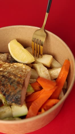 grilled fish with vegetables in a brown container