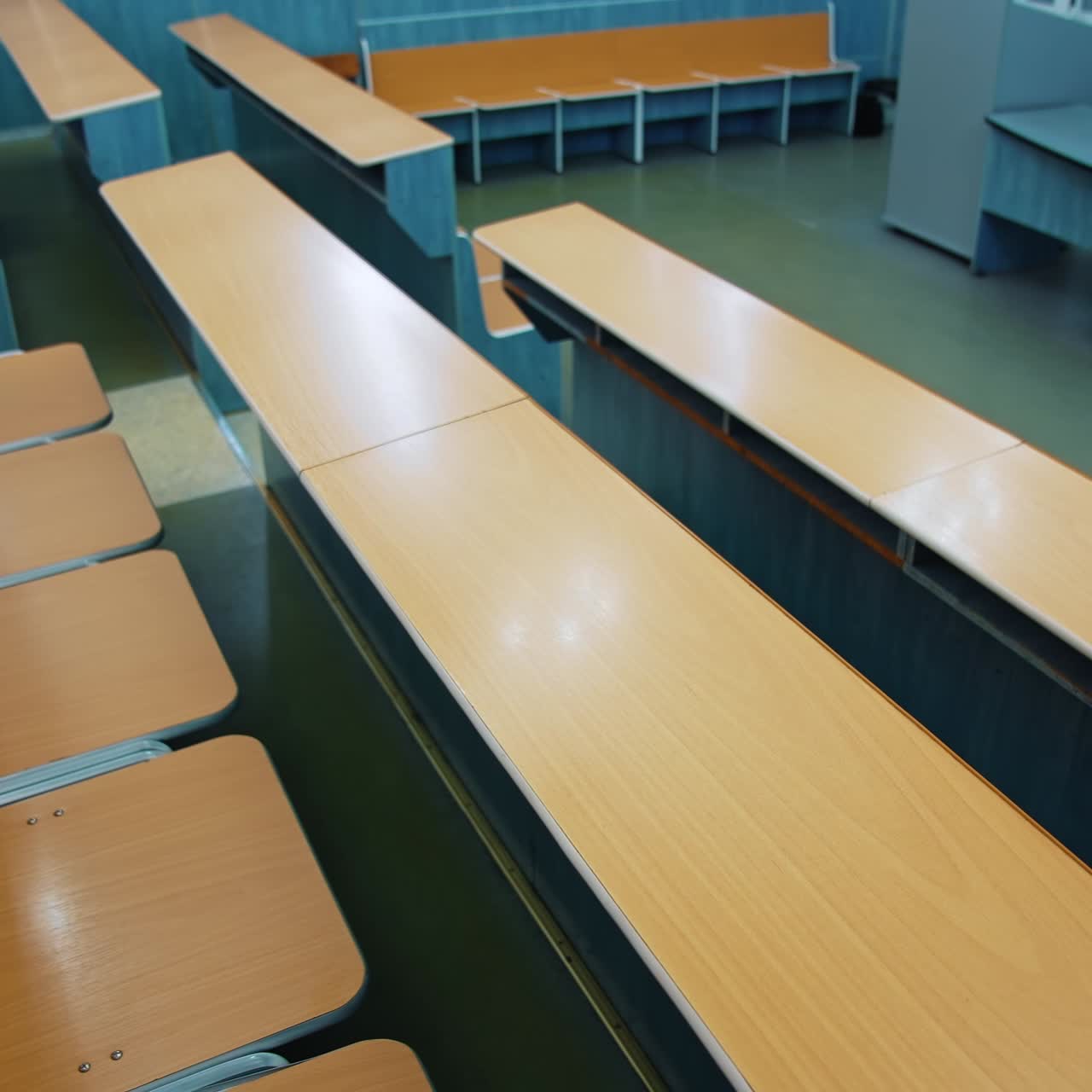 Empty auditorium for students. Rows of wooden tables and chairs in the university. Nobody in the class during pandemic