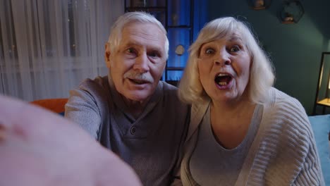 pov of mature grandfather grandmother making online video call talking waving hand looking at camera