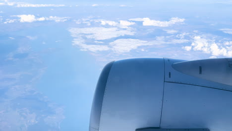 Aerial-view-of-clouds-and-earth-seen-from-airplane-window,-engine-in-shot