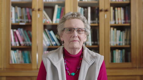 portrait of confident elderly caucasian woman looking serious at camera sitting in library background